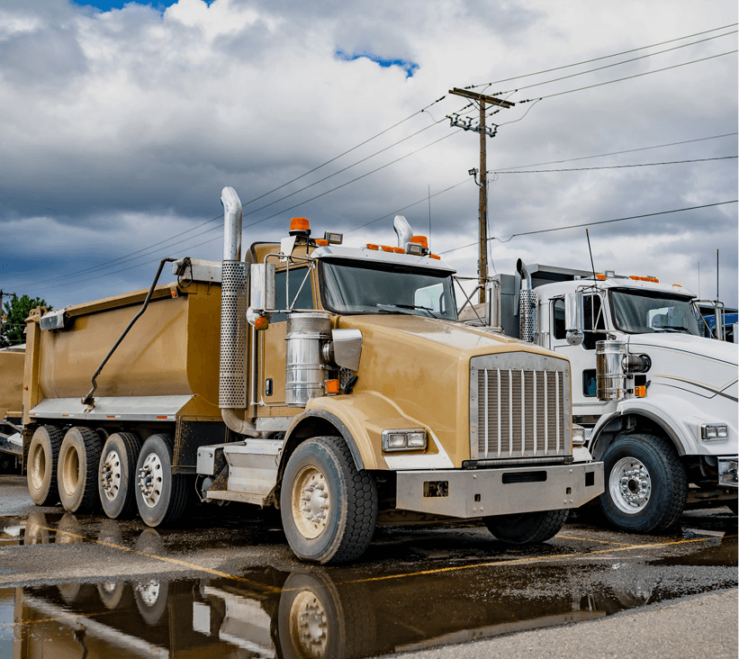 Parked dump trucks under cloudy sky